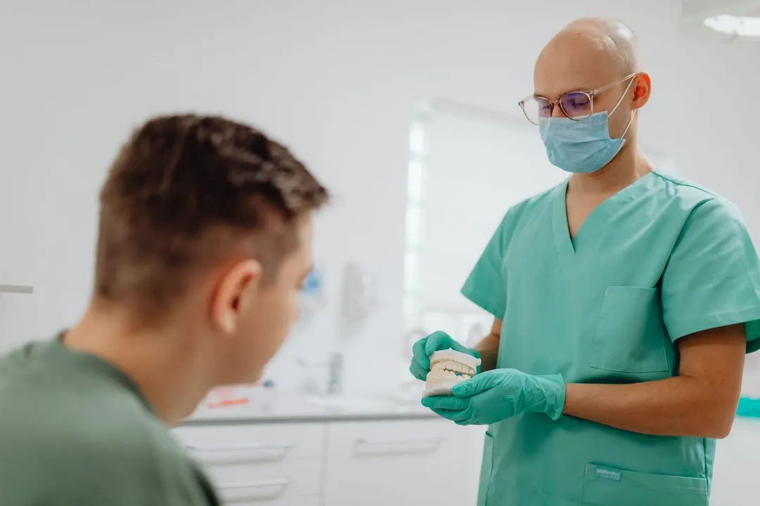 Medic stomatolog care îi explică unui pacient tânăr ce urmează
