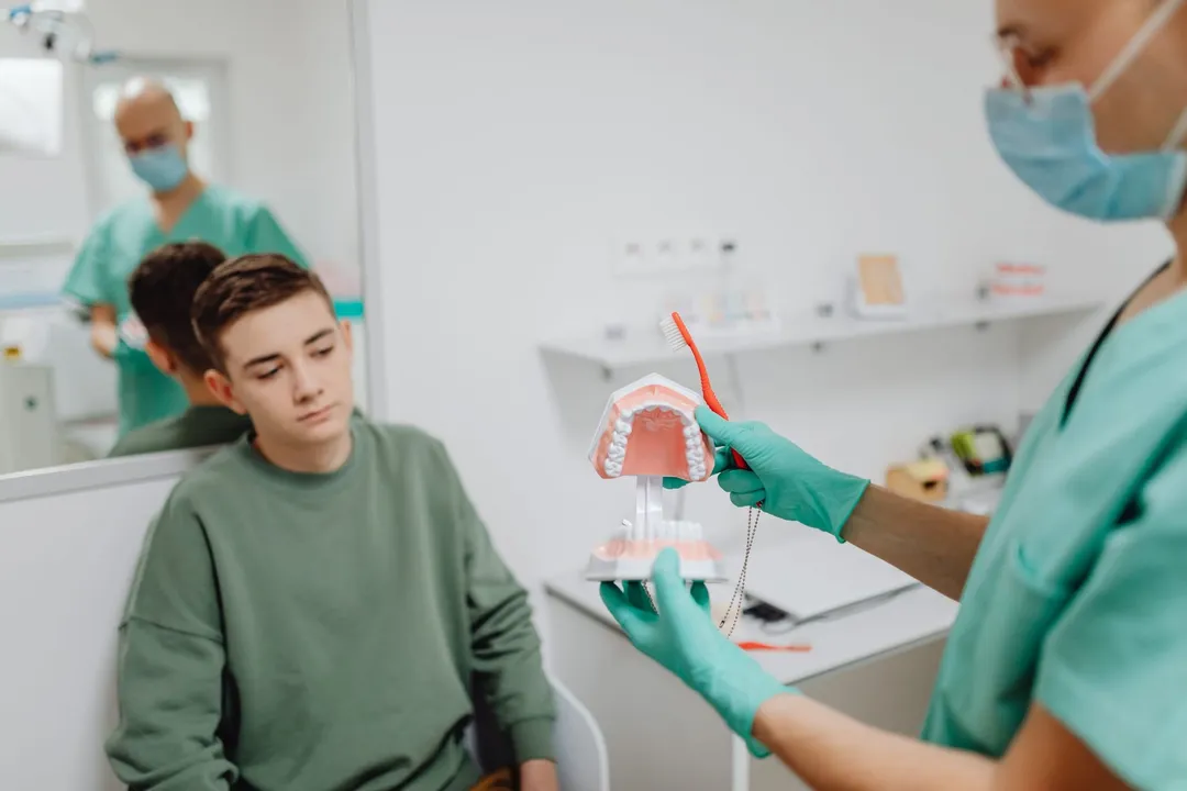 Adolescent căruia medicul îi explică tratamentul pe un model dentar